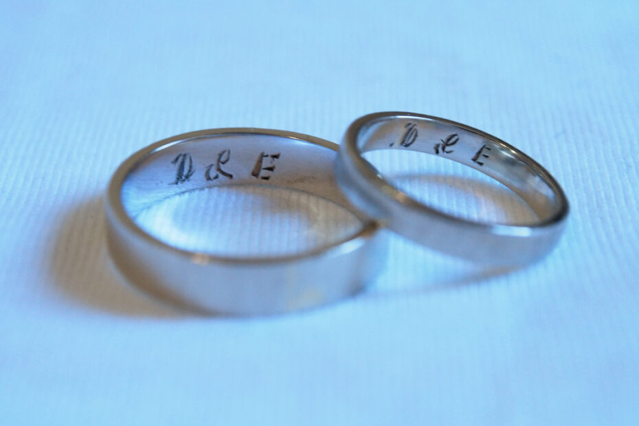 white gold bands by little white pouch engraved with initials D and E